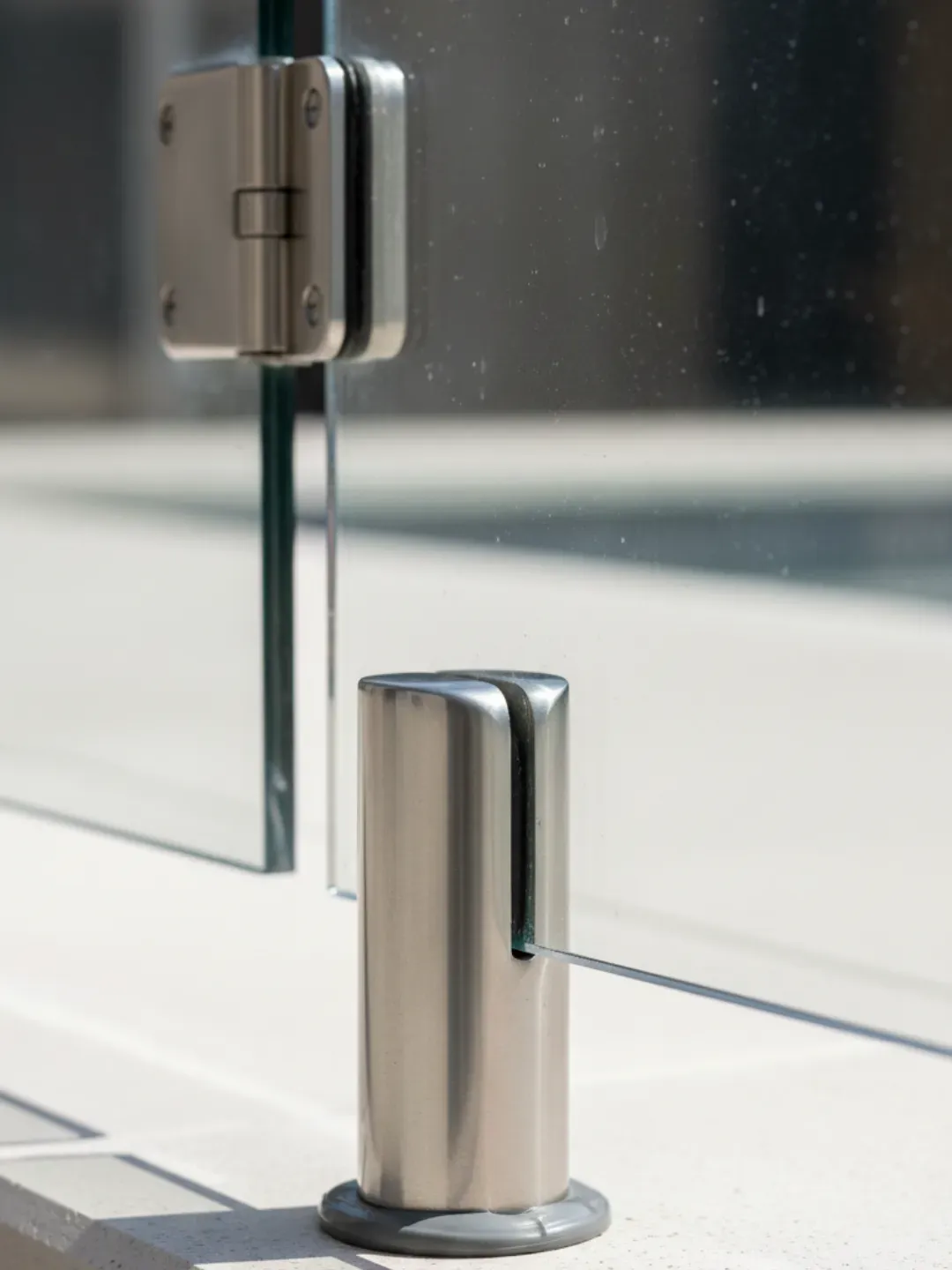 Marine-grade stainless steel spigots and hinge hardware supporting a frameless glass pool fence in Ascot.